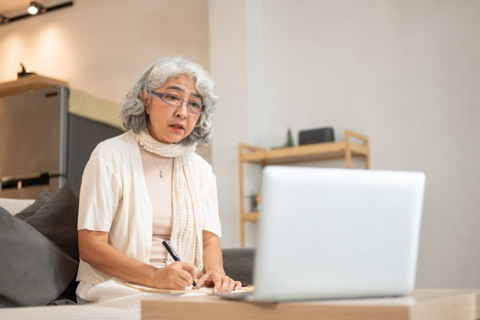 Woman watching webinar taking notes